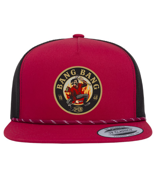 A red and black trucker hat featuring a circular 'Bang Bang' woven patch with a circular embroidered cartoon character holding fire fighter tools on the front panel.