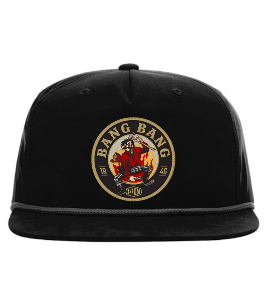 A black flat-brim baseball cap featuring a circular woven embroidered patch on the front with text that says 'BANG BANG' and a graphic of a cartoon character holding fire fighter tools.